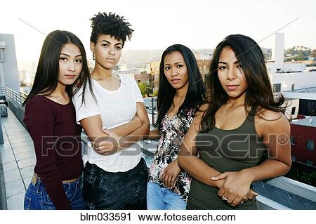 Stock Image - Serious women standing on urban rooftop. Fotosearch