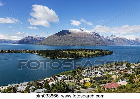 Stock Photograph - Snowcapped mountains and island in lake, Queenstown, Central Otago, New Zealand. Fotosearch