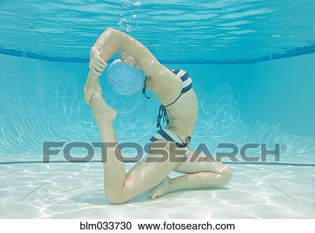 Stock Image - Underwater view of Caucasian woman practicing yoga in swimming pool. Fotosearch