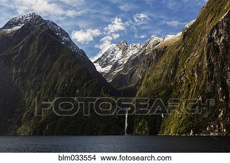 Picture - Waterfall from mountains over remote river, Milford Sound, Fiordland, New Zealand. Fotosearch