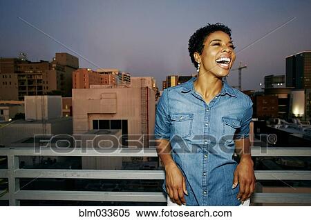 Stock Photography - Woman laughing on urban rooftop. Fotosearch