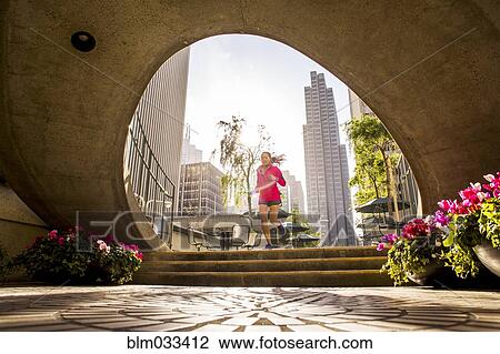 Stock Image - Woman running in urban park. Fotosearch