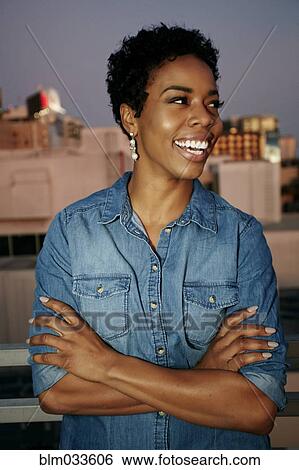 Stock Photograph - Woman smiling on urban rooftop. Fotosearch