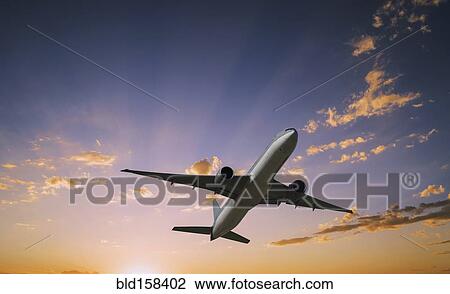 Airplane flying in dramatic sunset sky View Large Photo Image Stock Image - Airplane flying in dramatic sunset sky. Fotosearch