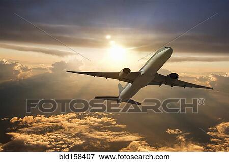 Airplane flying in dramatic sunset sky View Large Photo Image Stock Photo - Airplane flying in dramatic sunset sky. Fotosearch