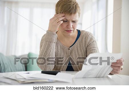 Stock Image - Anxious Caucasian woman paying bills. Fotosearch