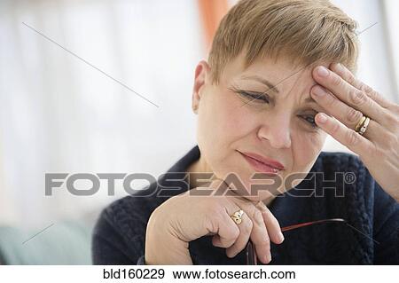 Stock Photo - Anxious Caucasian woman rubbing forehead. Fotosearch
