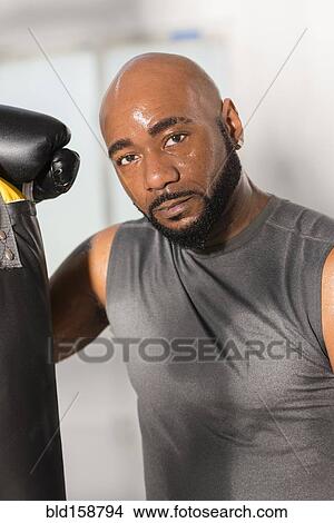 Picture - Black boxer training with punching bag. Fotosearch