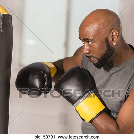 Stock Image - Black boxer training with punching bag. Fotosearch