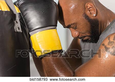 Stock Image - Black boxer training with punching bag. Fotosearch