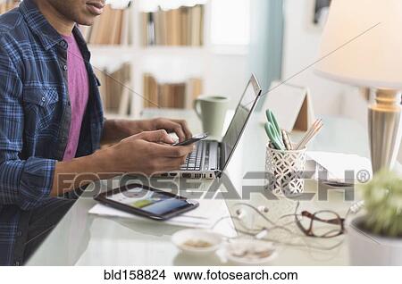 Picture - Black businessman multi-tasking at desk. Fotosearch