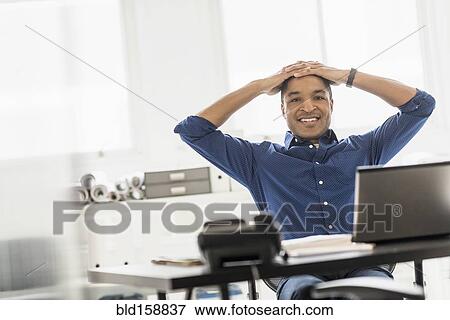Black businessman smiling at office desk View Large Photo Image Stock Photo - Black businessman smiling at office desk. Fotosearch