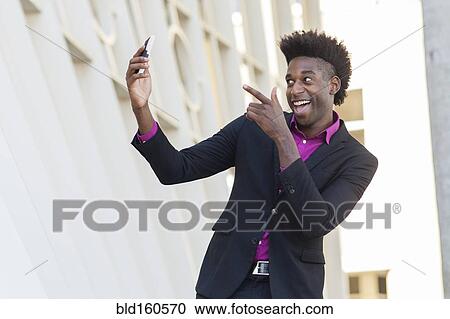 Black businessman taking selfie outside building View Large Photo Image Stock Image - Black businessman taking selfie outside building. Fotosearch