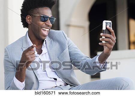 Black businessman taking selfie outside building View Large Photo Image Stock Image - Black businessman taking selfie outside building. Fotosearch
