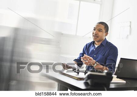 Black businessman talking at office desk View Large Photo Image Picture - Black businessman talking at office desk. Fotosearch