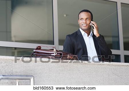 Stock Image - Black businessman talking on cell phone. Fotosearch