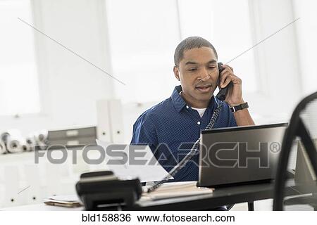 Stock Photograph - Black businessman talking on telephone in office. Fotosearch