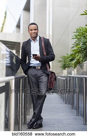 Black businessman using cell phone outside building View Large Photo Image Stock Photo - Black businessman using cell phone outside building. Fotosearch