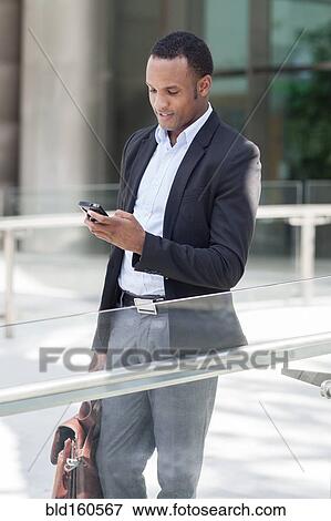 Black businessman using cell phone outdoors View Large Photo Image Stock Photo - Black businessman using cell phone outdoors. Fotosearch