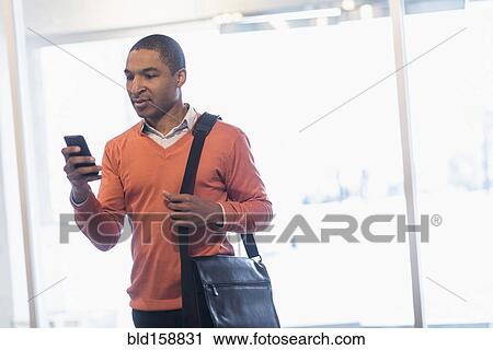 Stock Image - Black businessman with cell phone and messenger bag. Fotosearch
