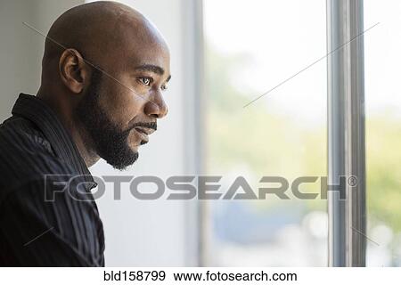 Stock Photo - Black man looking out window. Fotosearch