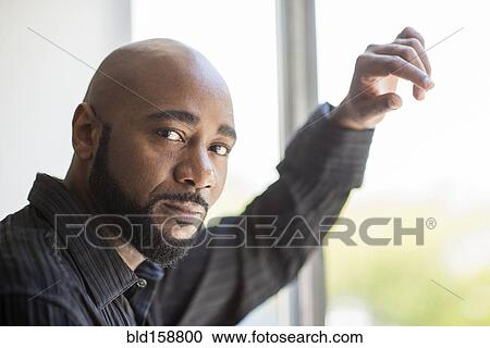 Black man standing at window View Large Photo Image Stock Image - Black man standing at window. Fotosearch
