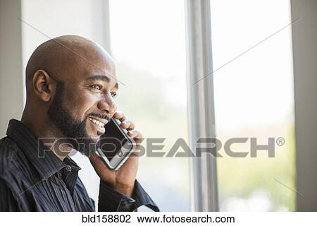 Black man talking on cell phone near window View Large Photo Image Stock Image - Black man talking on cell phone near window. Fotosearch