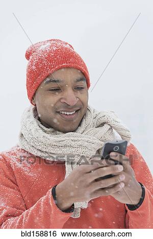 Stock Photograph - Black man using cell phone in snow. Fotosearch