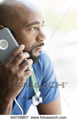 Black nurse talking on cell phone near window View Large Photo Image Stock Photo - Black nurse talking on cell phone near window. Fotosearch