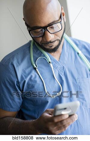 Black nurse using cell phone View Large Photo Image Stock Photo - Black nurse using cell phone. Fotosearch
