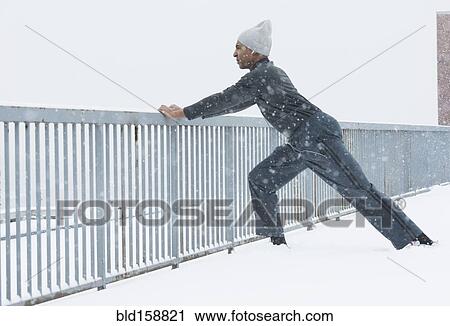 Stock Image - Black runner stretching in snow. Fotosearch
