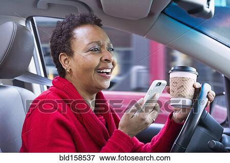 Black woman using cell phone and drinking coffee while driving car View Large Photo Image Stock Photo - Black woman using cell phone and drinking coffee while driving car. Fotosearch