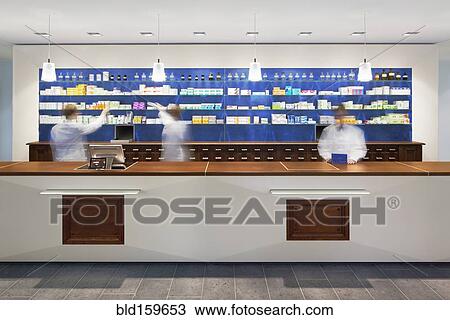 Stock Image - Blurred view of pharmacists behind counter in modern pharmacy. Fotosearch