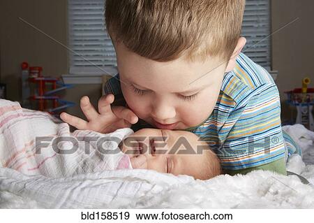 Boy admiring newborn sibling on bed View Large Photo Image Stock Photo - Boy admiring newborn sibling on bed. Fotosearch