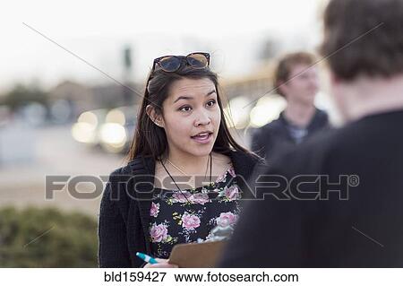 Stock Photo - Canvasser with clipboard talking to man. Fotosearch