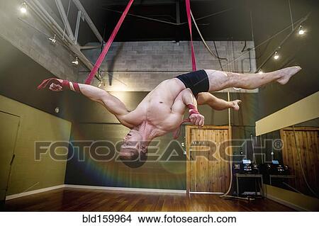 Caucasian acrobat hanging from ropes in studio View Large Photo Image Picture - Caucasian acrobat hanging from ropes in studio. Fotosearch