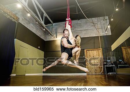 Stock Photography - Caucasian acrobats hanging from ropes in studio. Fotosearch