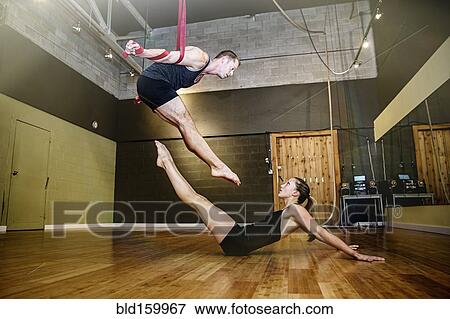 Stock Photo - Caucasian acrobats training on ropes in studio. Fotosearch