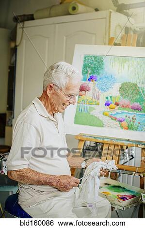 Stock Photograph - Caucasian artist cleaning brushes in studio. Fotosearch