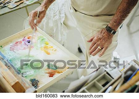 Stock Image - Caucasian artist mixing paint in palette in studio. Fotosearch