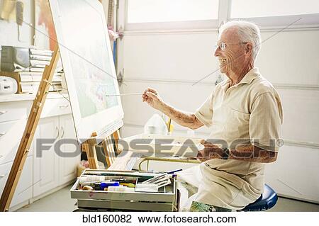 Stock Image - Caucasian artist painting in garage. Fotosearch