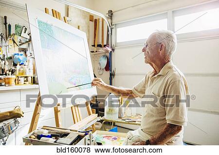 Stock Photo - Caucasian artist painting in garage. Fotosearch