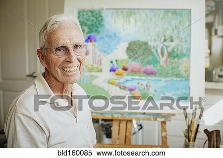 Stock Photography - Caucasian artist smiling with painting in studio. Fotosearch