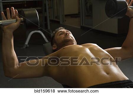Stock Photo - Caucasian athlete lifting weights in gymnasium. Fotosearch