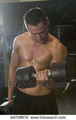 Stock Photo - Caucasian athlete lifting weights in gymnasium. Fotosearch