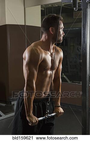 Stock Image - Caucasian athlete using exercise machine in gymnasium. Fotosearch