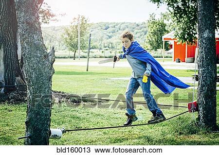 Stock Image - Caucasian boy in costume balancing on tightrope. Fotosearch
