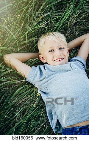 Caucasian boy laying in tall grass View Large Photo Image Stock Photograph - Caucasian boy laying in tall grass. Fotosearch
