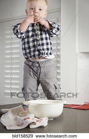 Stock Photo - Caucasian boy standing on table playing with food. Fotosearch