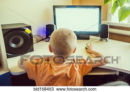 Stock Image - Caucasian boy using computer at desk. Fotosearch